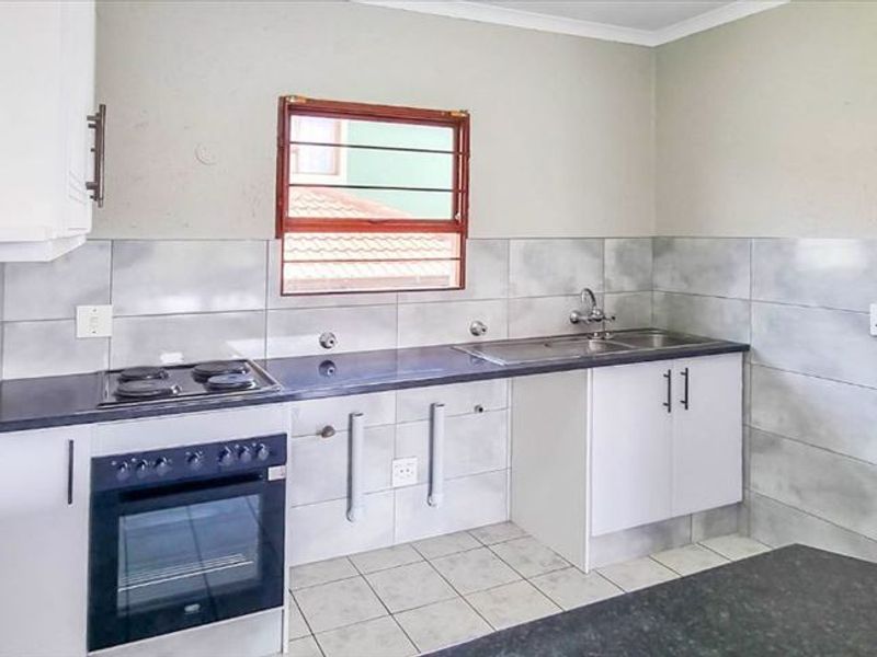 A functional kitchen featuring built-in cabinetry, a stainless steel sink, an integrated oven with an electric hob, and tiled splashbacks.