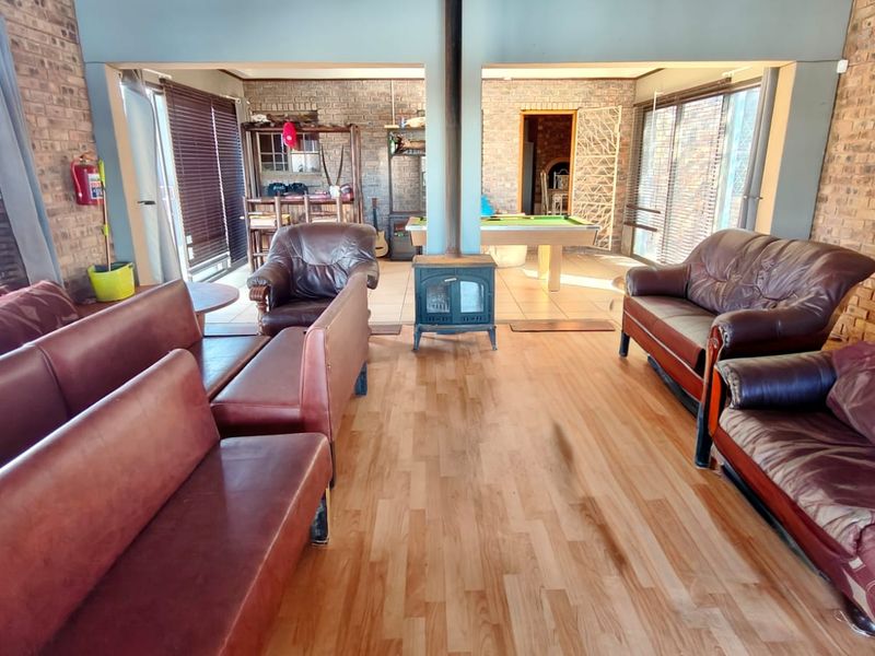 Spacious open-plan living area featuring exposed brick walls, laminate flooring, and a central wood-burning stove, with direct access to outdoor spaces.