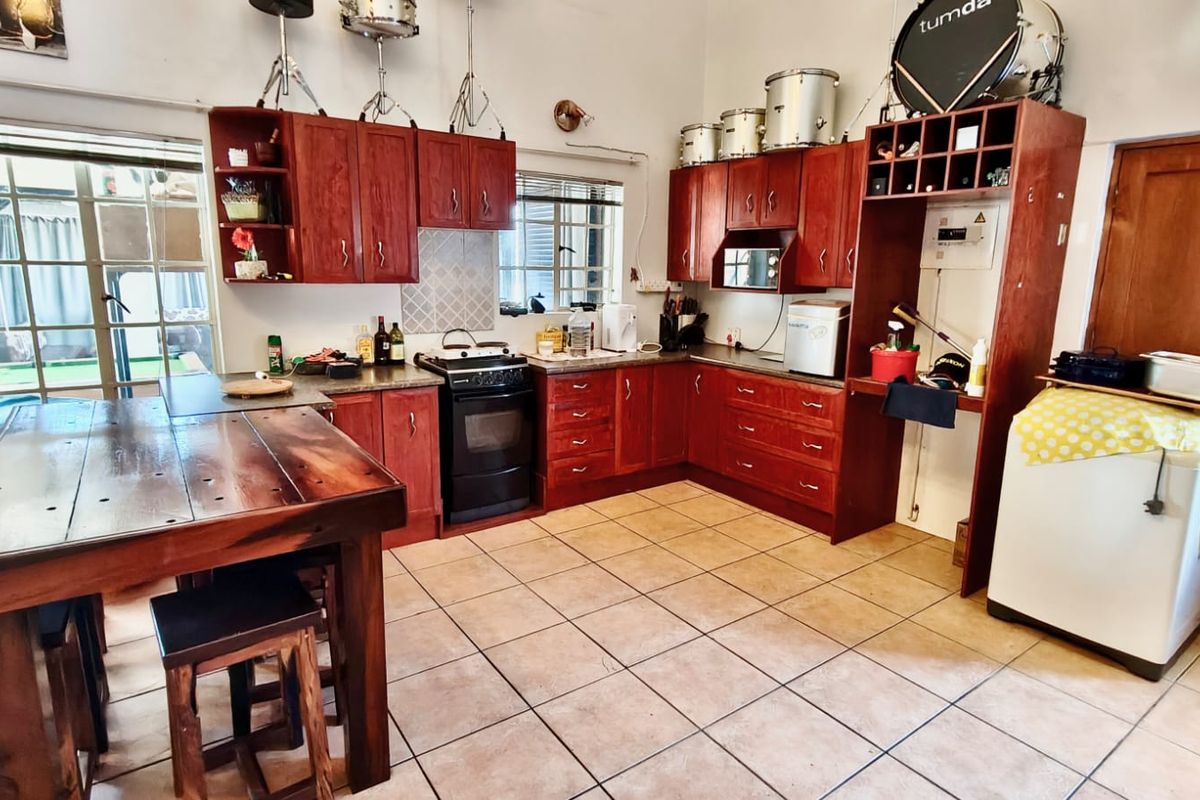 A functional kitchen featuring warm-toned wooden cabinetry, tiled flooring, and a freestanding stove, offering a practical layout with ample storage space.