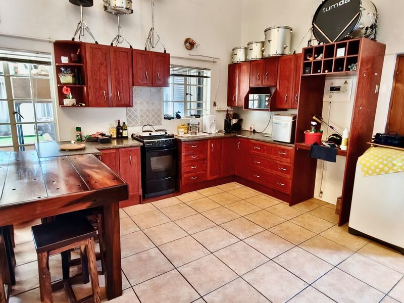 A functional kitchen featuring warm-toned wooden cabinetry, tiled flooring, and a freestanding stove, offering a practical layout with ample storage space.