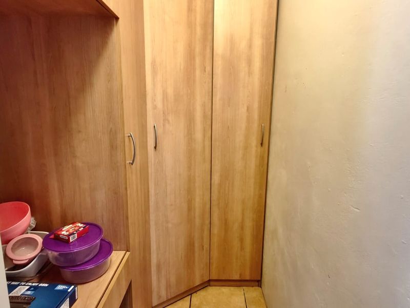 A functional scullery or pantry area featuring built-in wooden cabinetry and tiled flooring, providing additional storage space.
