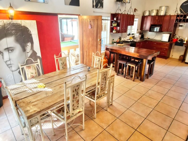 Open-plan kitchen and dining area featuring tiled floors, wooden cabinetry, and a central kitchen island with integrated seating.