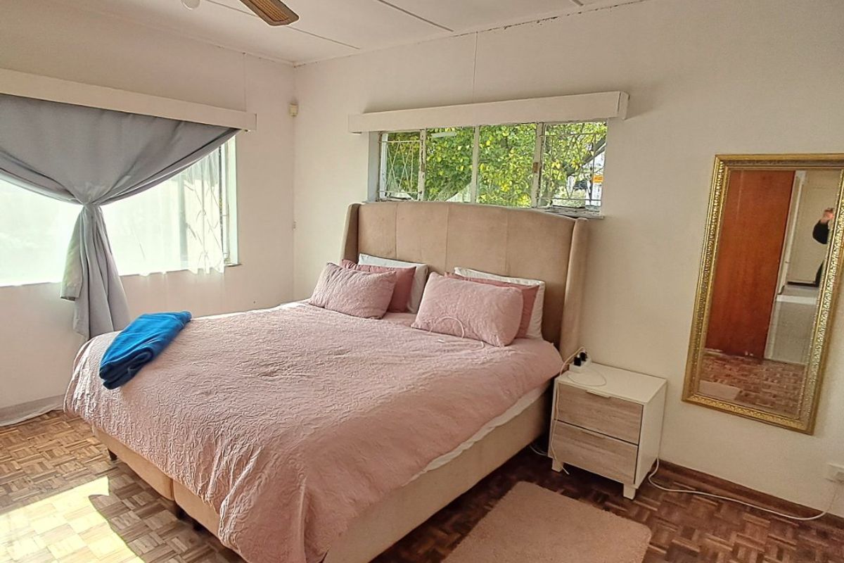 A bedroom featuring original parquet flooring, a ceiling fan, and steel-framed windows, offering a classic foundation for potential cosmetic updates.