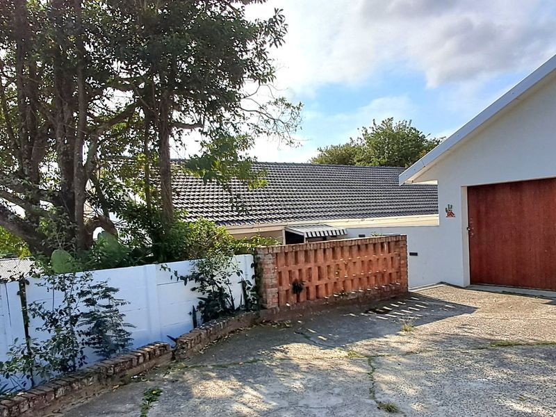 Front exterior view showing a concrete driveway, brick and precast boundary walls, and a garage entrance with a tiled roof structure.