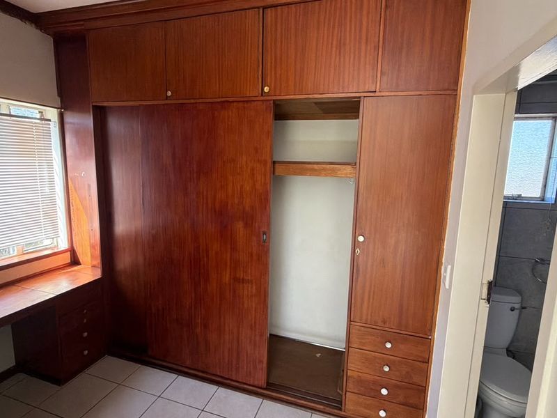 Bedroom featuring extensive built-in wooden cabinetry, integrated desk space, and tiled flooring, offering functional storage and workspace potential.
