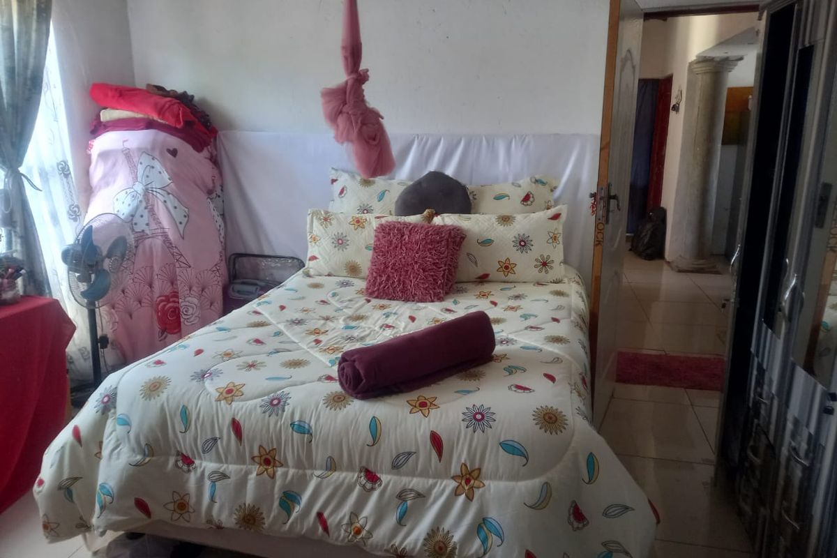 A bedroom featuring tiled flooring and access to an adjacent hallway area.