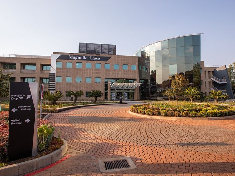 Professional exterior view of Magnolia Close commercial office building featuring a paved circular driveway, modern glass facade, and well-maintained landscaped grounds.