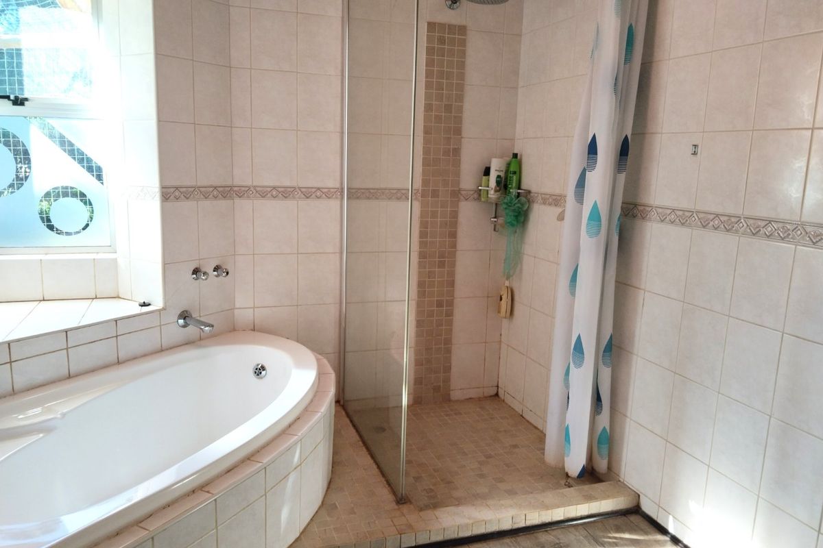 A functional bathroom featuring a built-in bathtub and a separate walk-in shower with glass screen and neutral ceramic tiling.