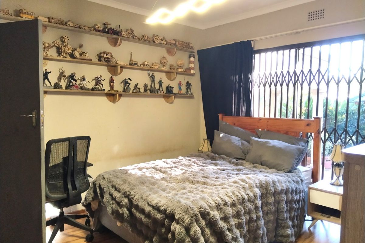 A bedroom featuring laminate flooring, a security gate on the window, and wall-mounted shelving units.