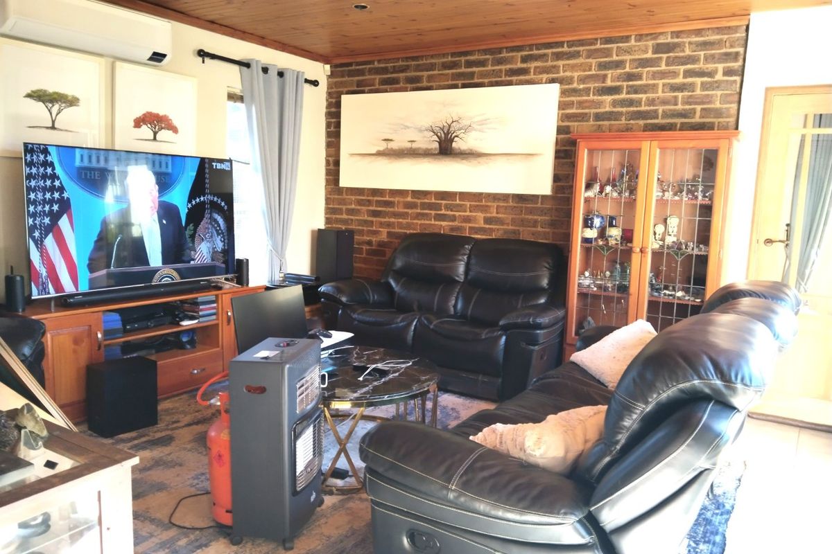 A living room featuring an exposed brick feature wall, timber ceiling, and tiled flooring, equipped with a wall-mounted split system air conditioner.