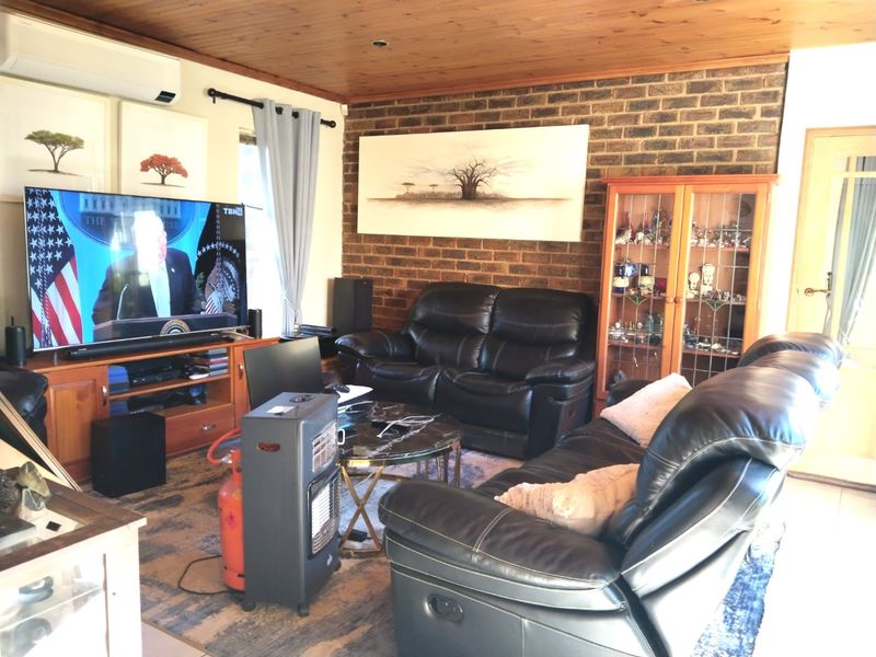 A living room featuring an exposed brick feature wall, timber ceiling, and tiled flooring, equipped with a wall-mounted split system air conditioner.