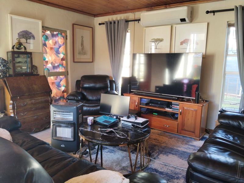 A comfortable living room featuring a timber ceiling, split-system air conditioning, and a decorative stained glass door.