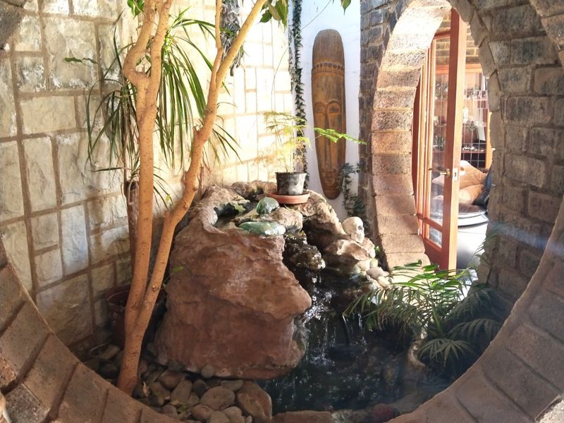 A unique outdoor courtyard area featuring a circular brick archway, stone wall cladding, and a built-in rock water feature.