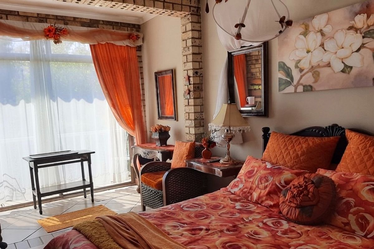 A bedroom featuring an exposed brick pillar, tiled flooring, and a large sliding glass door providing natural light.