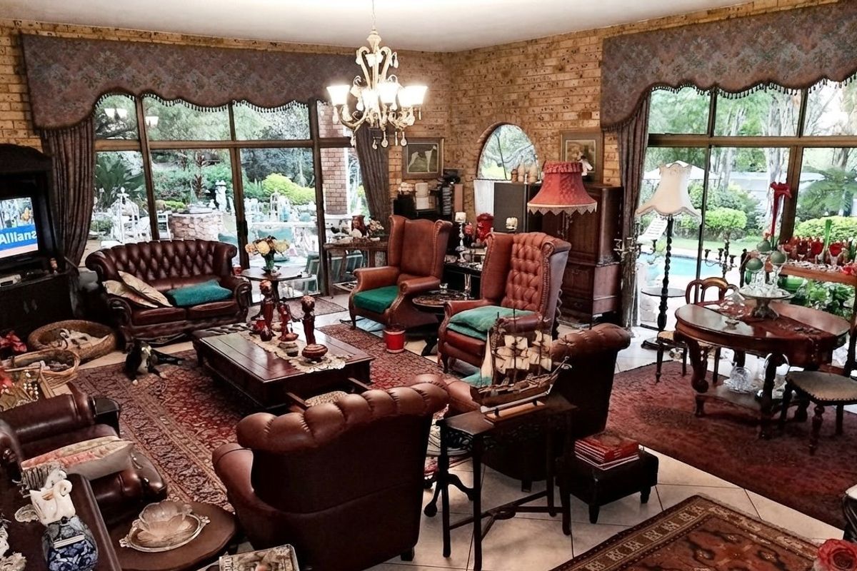 Spacious living area featuring exposed brick walls, large glass sliding doors providing garden views, and tiled flooring, offering a classic and warm atmosphere.