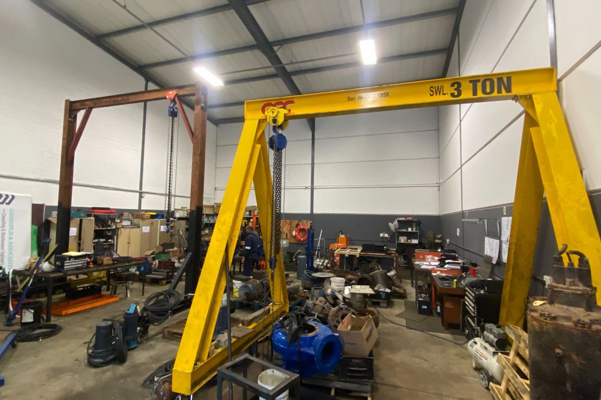 Spacious industrial workshop featuring high ceilings, exposed steel trusses, and a heavy-duty gantry crane, suitable for manufacturing or maintenance operations.