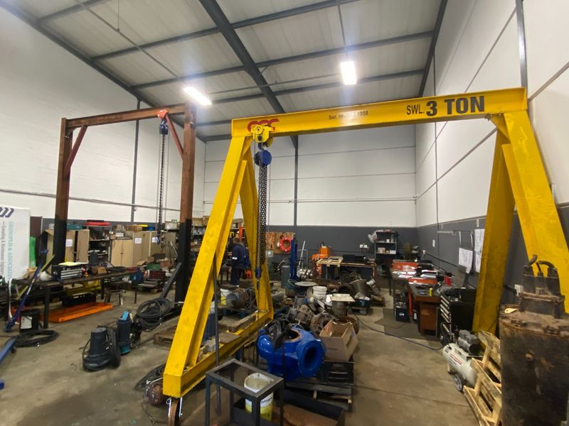 Spacious industrial workshop featuring high ceilings, exposed steel trusses, and a heavy-duty gantry crane, suitable for manufacturing or maintenance operations.