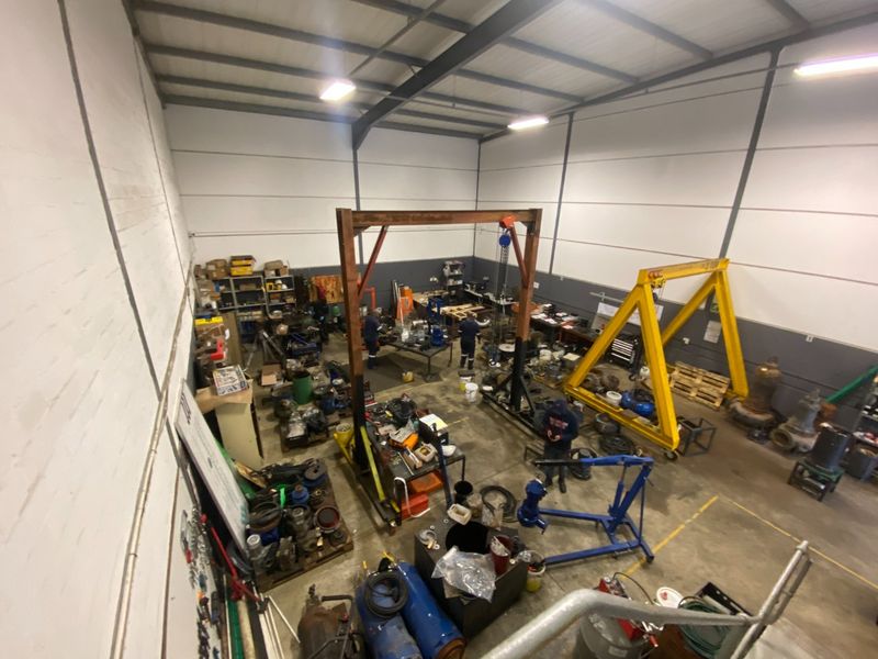 Spacious industrial workshop featuring high ceilings, exposed steel trusses, concrete flooring, and heavy-duty gantry cranes suitable for manufacturing or maintenance operations.