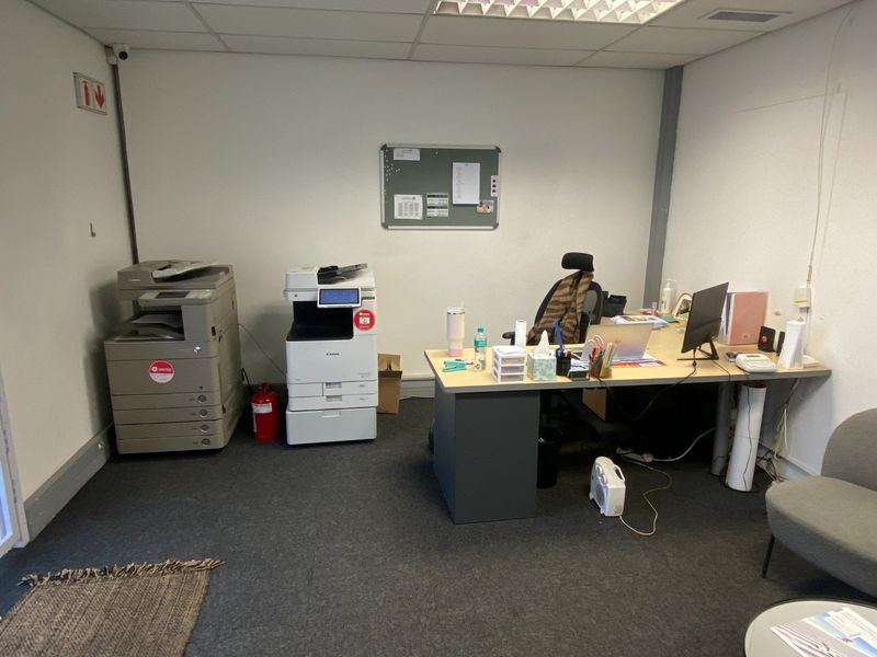 A functional office space featuring carpeted flooring, suspended ceiling with recessed lighting, and integrated security infrastructure.
