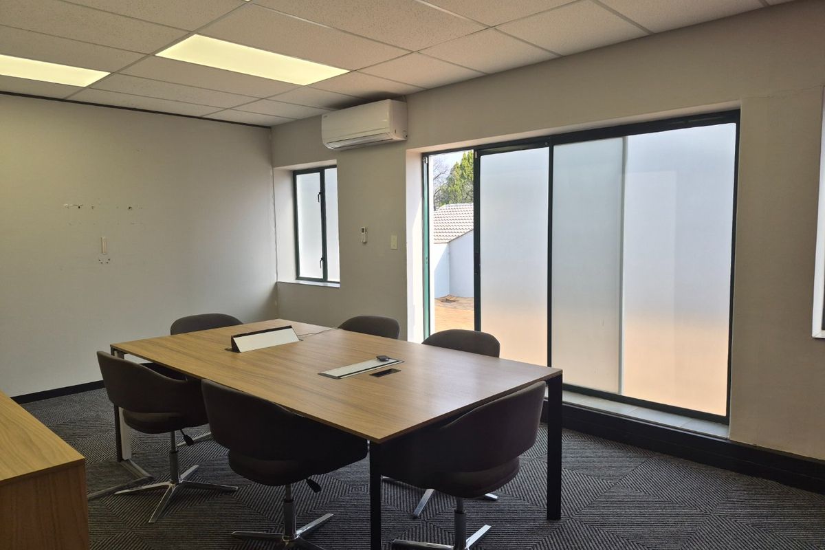 A professional office space featuring a suspended ceiling, recessed lighting, split-system air conditioning, and large sliding glass doors providing natural light.