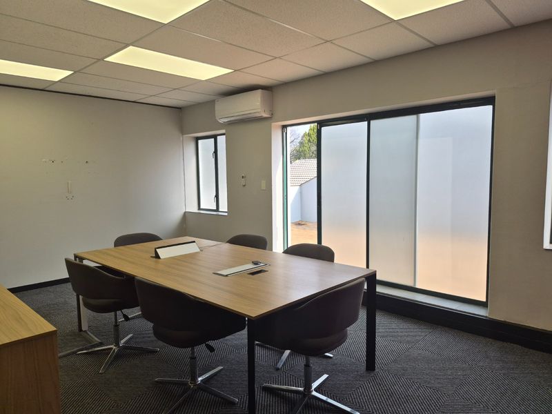 A professional office space featuring a suspended ceiling, recessed lighting, split-system air conditioning, and large sliding glass doors providing natural light.
