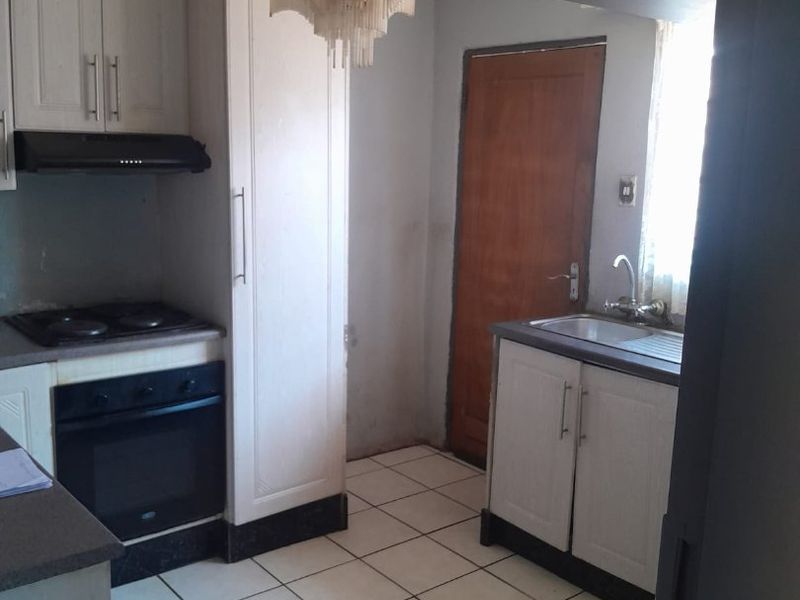 A dated kitchen featuring built-in cabinetry, oven, hob, and tiled flooring, requiring cosmetic updates to modernize the space.