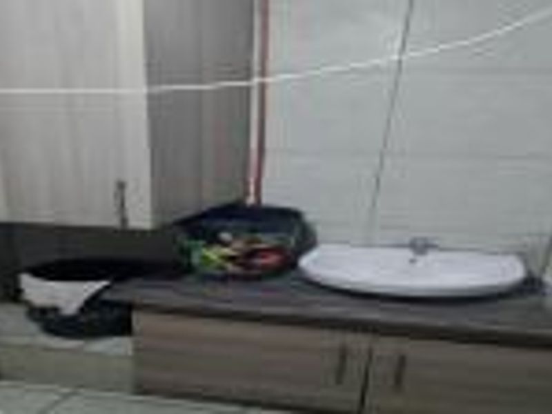 A functional laundry area featuring built-in cabinetry, a countertop, and a wash basin with tiled wall finishes.