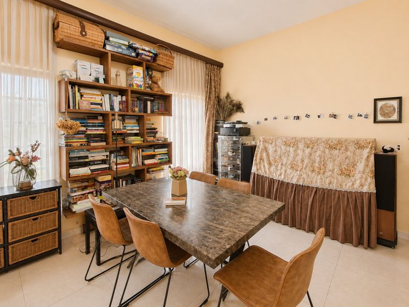 A dining room featuring tiled flooring and a large built-in wooden shelving unit, providing ample storage space for books and decorative items.