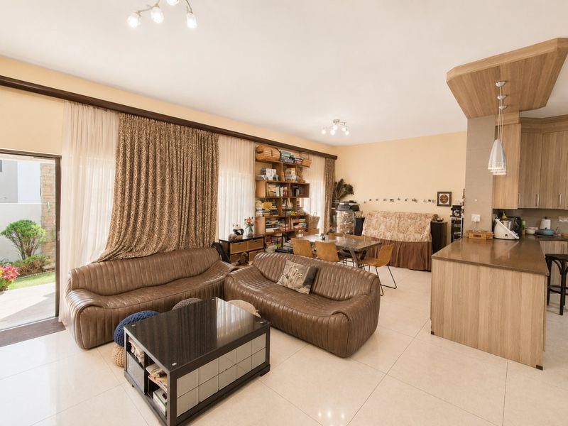 Spacious open-plan living and dining area featuring tiled floors, modern kitchen cabinetry with stone countertops, and direct access to an outdoor patio.
