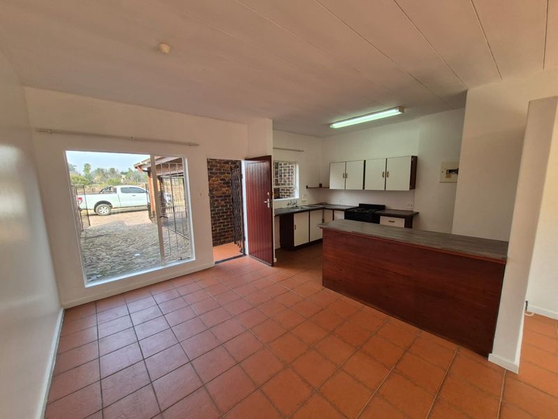 Open plan kitchen and living area featuring tiled floors, a breakfast bar, and direct access to the exterior through a sliding glass door.