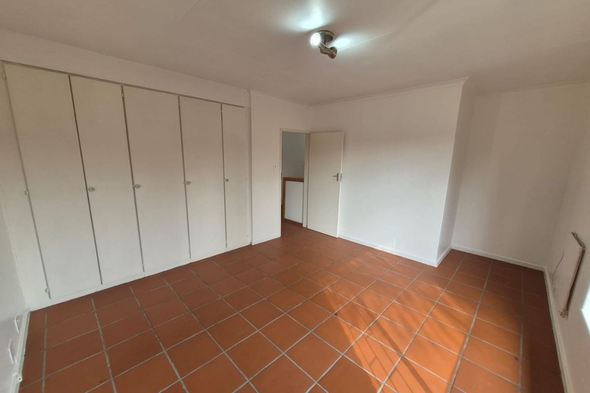 An empty bedroom featuring built-in cupboards and terracotta floor tiles, offering a blank canvas for personalization.