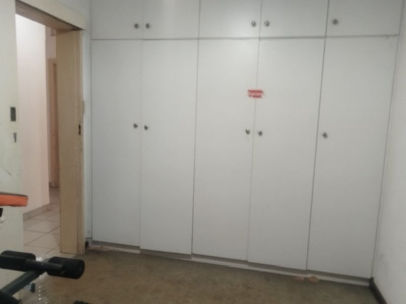 A bedroom featuring extensive built-in white cabinetry, providing ample storage space. The room requires flooring updates and general maintenance.
