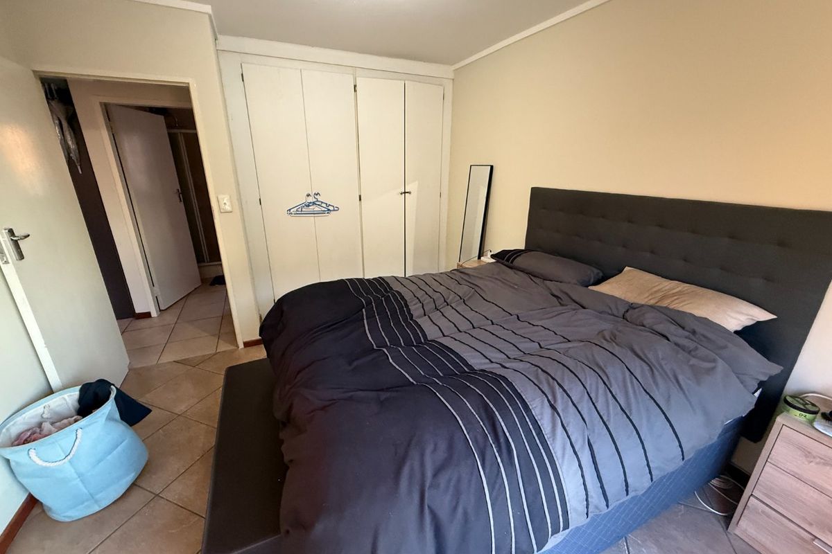 A bedroom featuring built-in cupboards and tiled flooring, providing a functional space with direct access to an adjacent room.