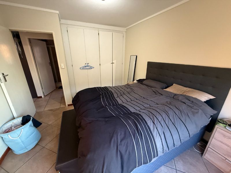 A bedroom featuring built-in cupboards and tiled flooring, providing a functional space with direct access to an adjacent room.