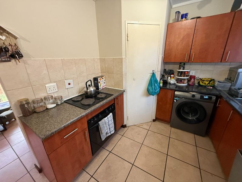 Compact kitchen featuring built-in cabinetry, laminate countertops, ceramic tile backsplash, and integrated electric cooking appliances with tiled flooring.