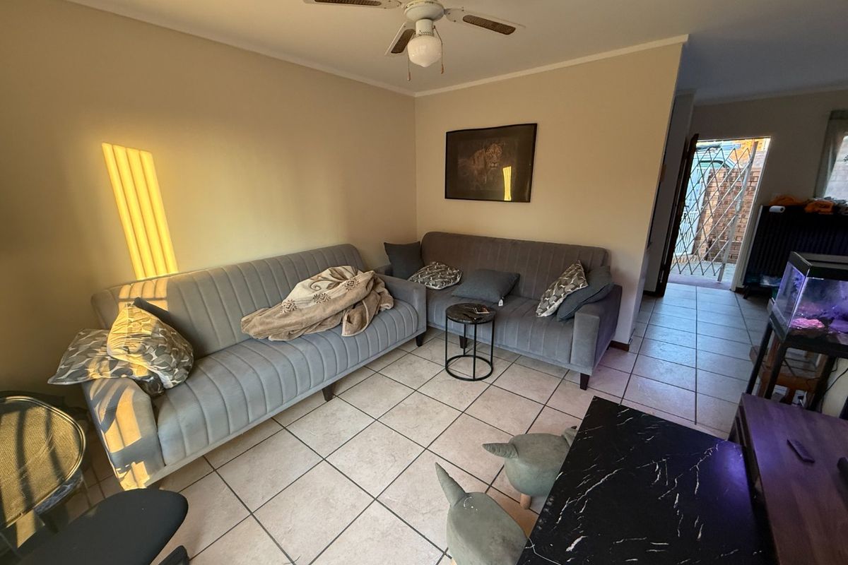 A living room featuring ceramic floor tiles and a ceiling fan, with an open transition to an exterior entrance area.
