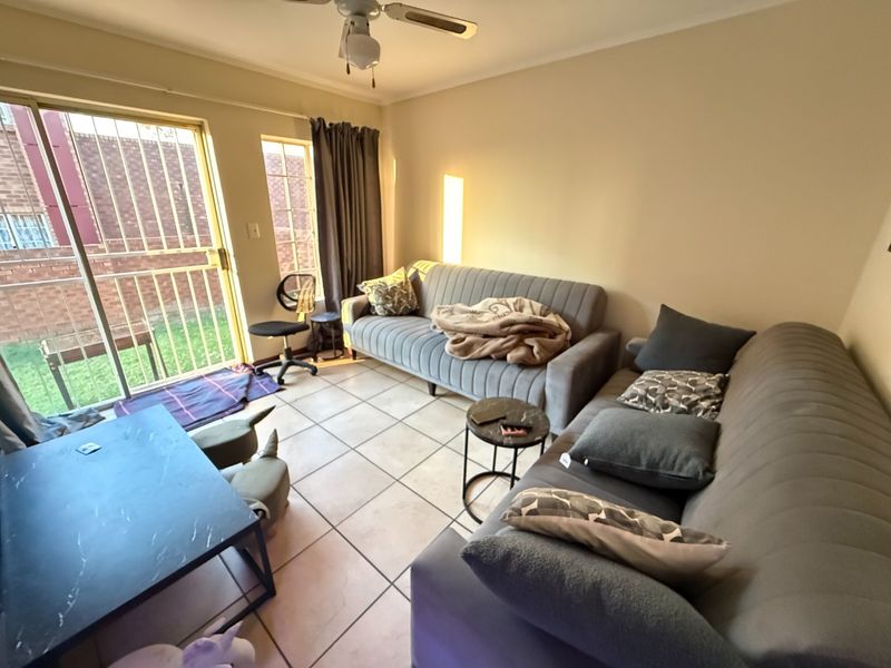 A living room featuring tiled flooring, a ceiling fan, and a sliding glass door providing access to the exterior.