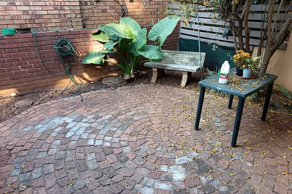 A private rear courtyard featuring circular brick paving, a brick retaining wall, and a timber privacy screen, offering potential for outdoor landscaping.