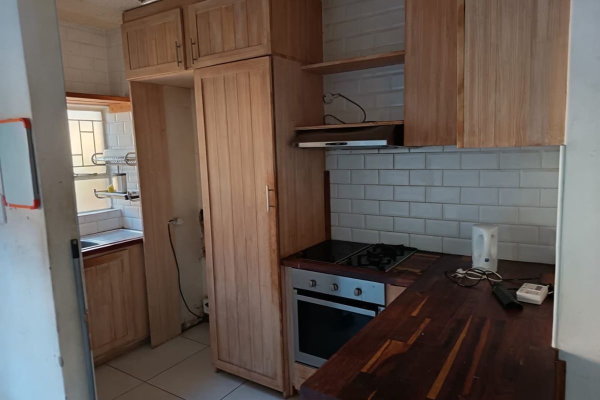 A functional kitchen featuring wooden cabinetry, subway tile backsplash, built-in oven with gas hob, and a wooden countertop.