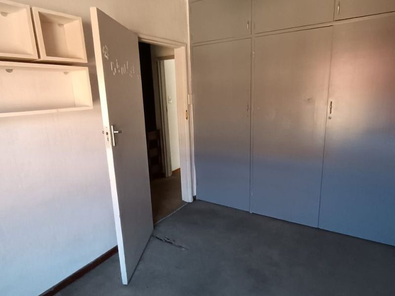 A vacant bedroom featuring built-in cupboards, a ceiling fan, and carpeted flooring, offering a blank canvas for potential updates and modernization.