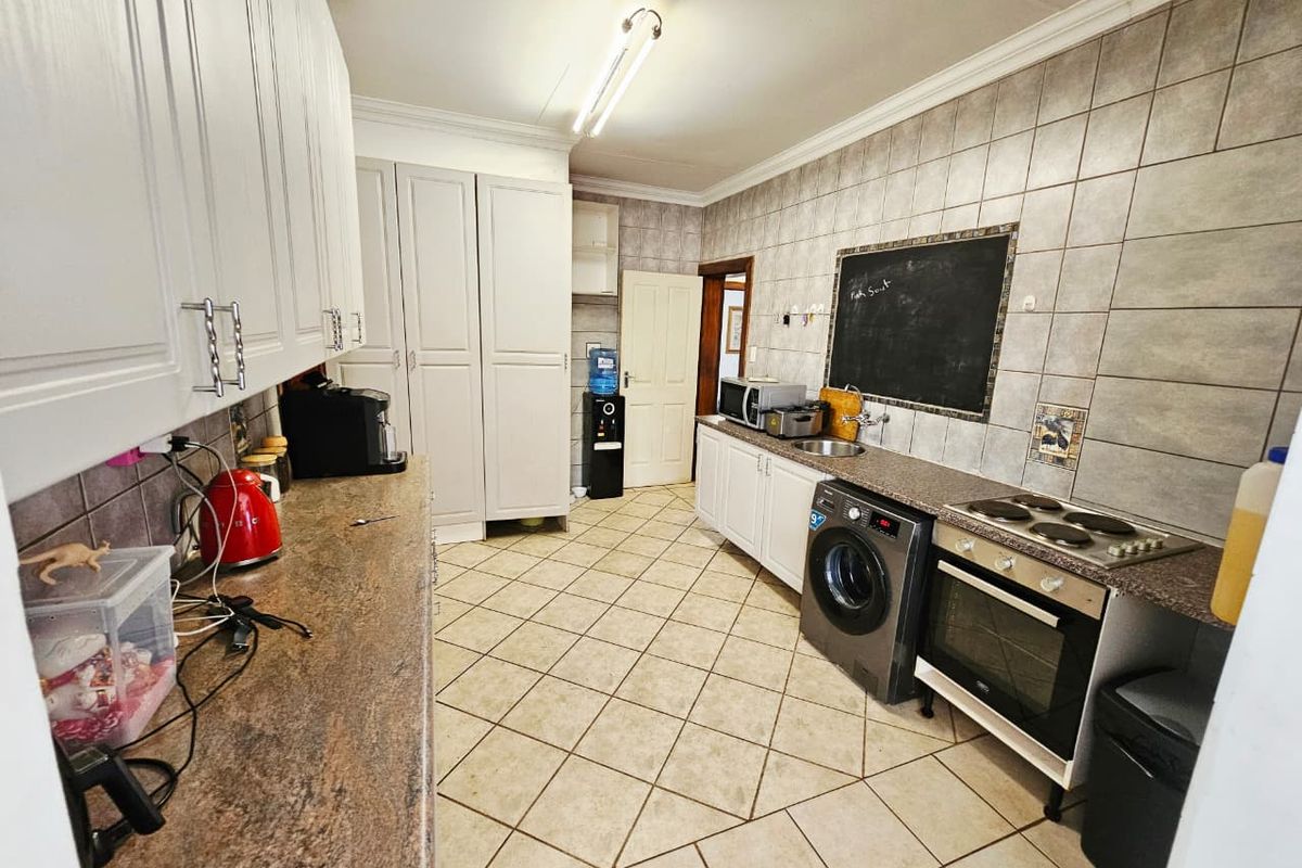 Functional kitchen featuring ample built-in cabinetry, laminate countertops, tiled backsplash, and integrated cooking appliances with ceramic floor tiling.