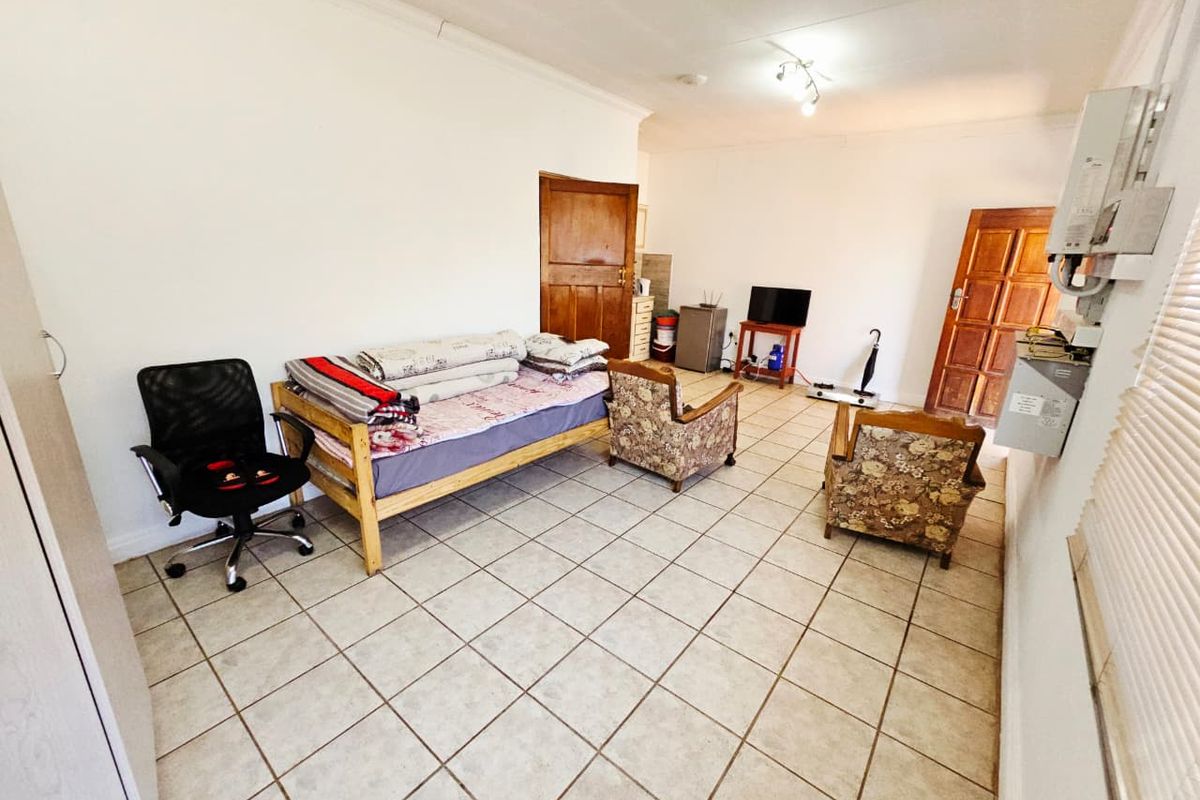 A living area featuring ceramic tiled flooring, timber panel doors, and coved cornicing, offering a functional space with potential for modernization.