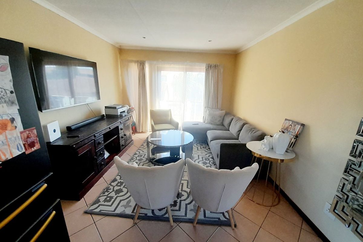 A comfortable living room featuring tiled flooring, recessed lighting, and a sliding glass door that provides natural light and access to the exterior.