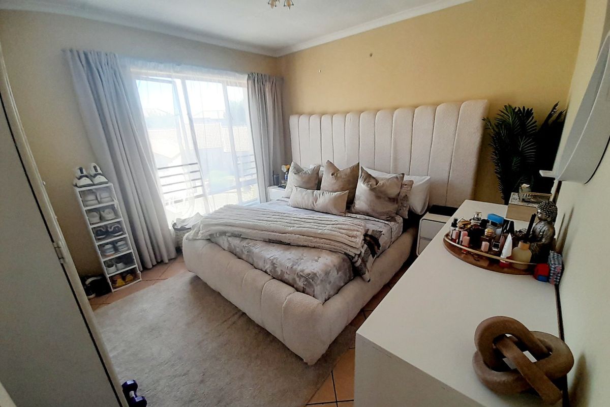 A well-lit bedroom featuring tiled flooring and a large sliding glass door providing natural light and access to the exterior.