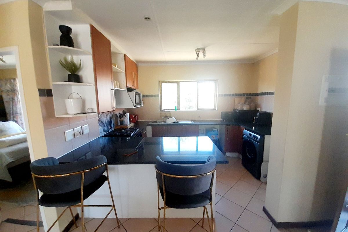 Functional kitchen featuring granite countertops, built-in cabinetry, a breakfast nook, and tiled flooring, offering a practical layout for daily meal preparation.