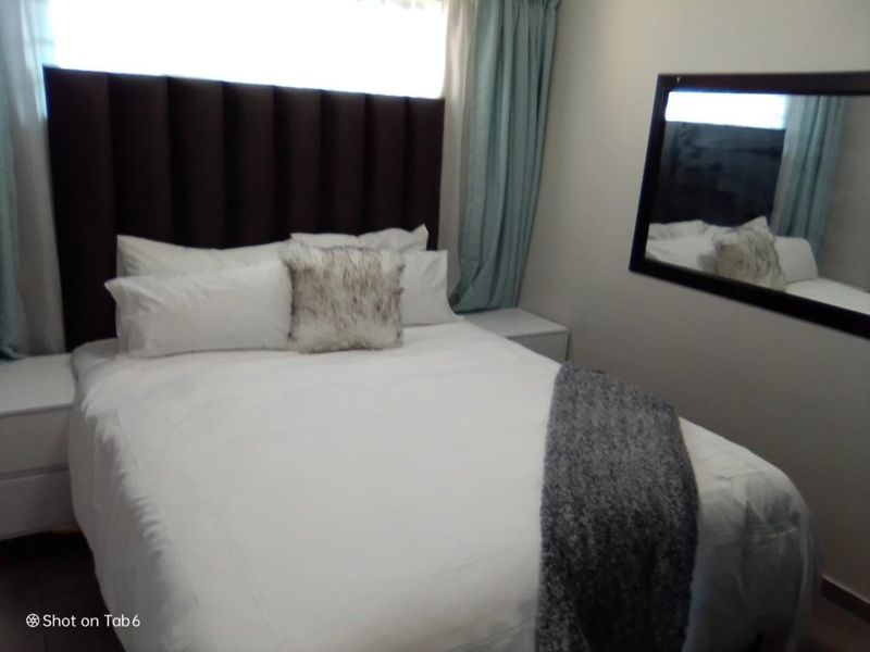 A compact bedroom featuring laminate flooring and a neutral color palette, providing a functional sleeping space.