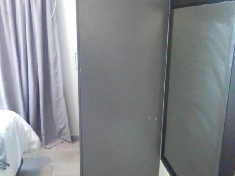 A bedroom interior featuring a dark built-in cupboard and tiled flooring.