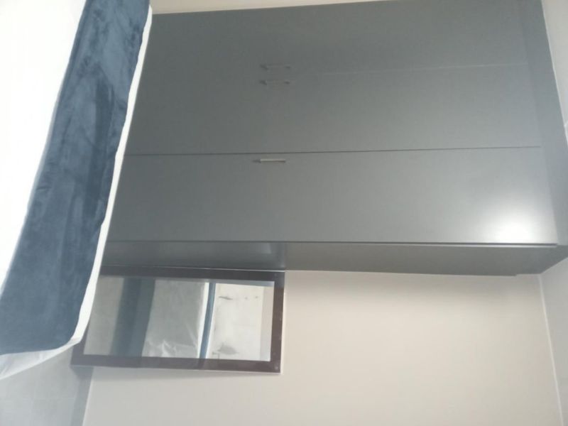 A bedroom featuring a modern, dark grey built-in wardrobe with clean lines and minimalist hardware.