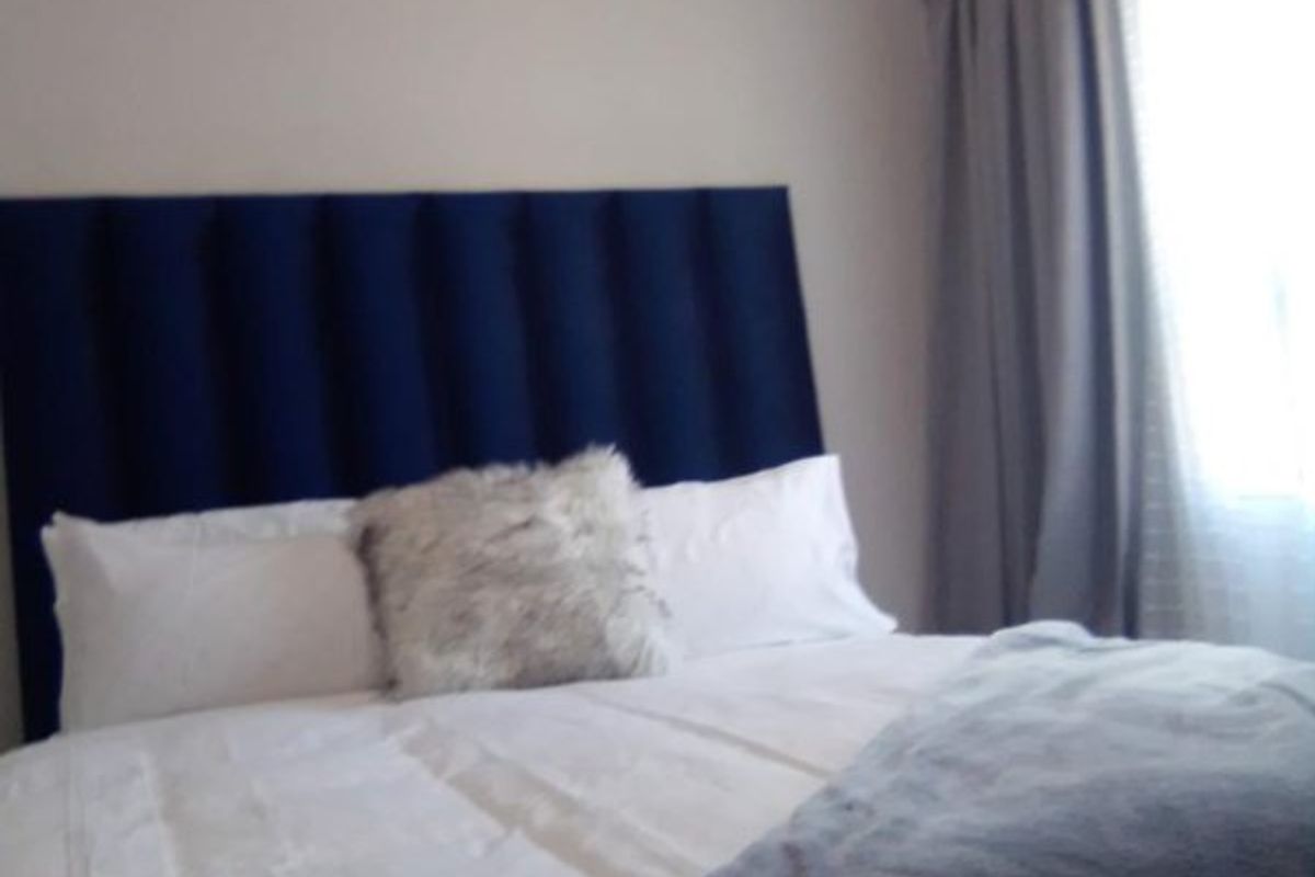 A bedroom featuring neutral wall tones and a window with curtains.