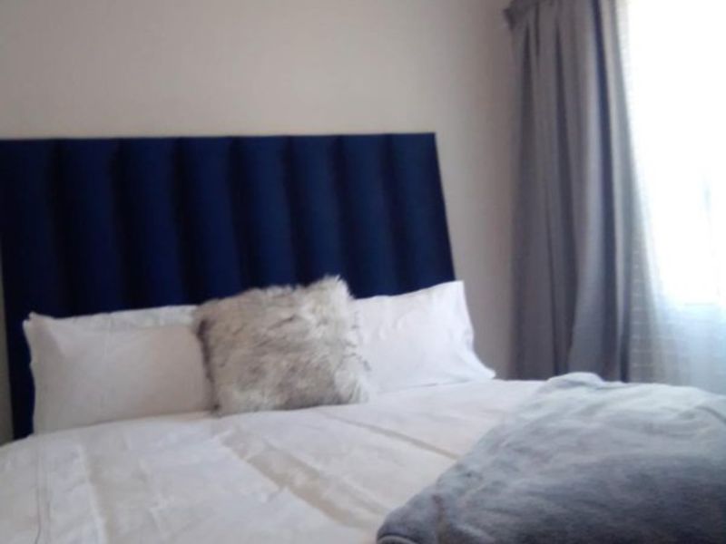 A bedroom featuring neutral wall tones and a window with curtains.